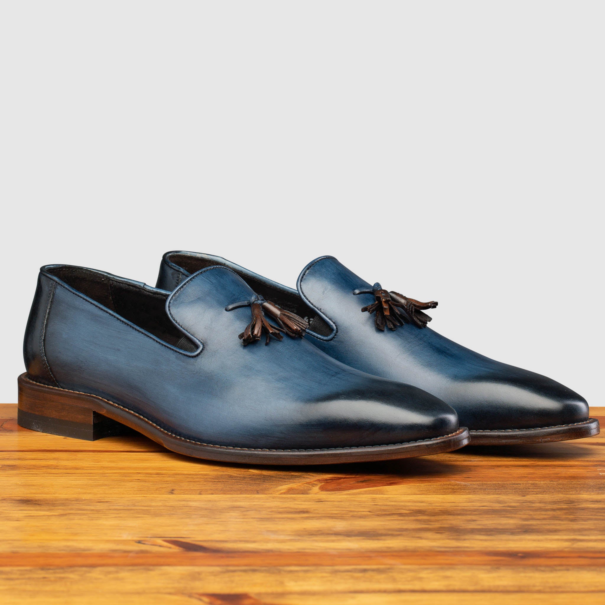Pair of Z993 Calzoleria Toscana Ocean Blue David Tassel Slip-On on top of a wooden table